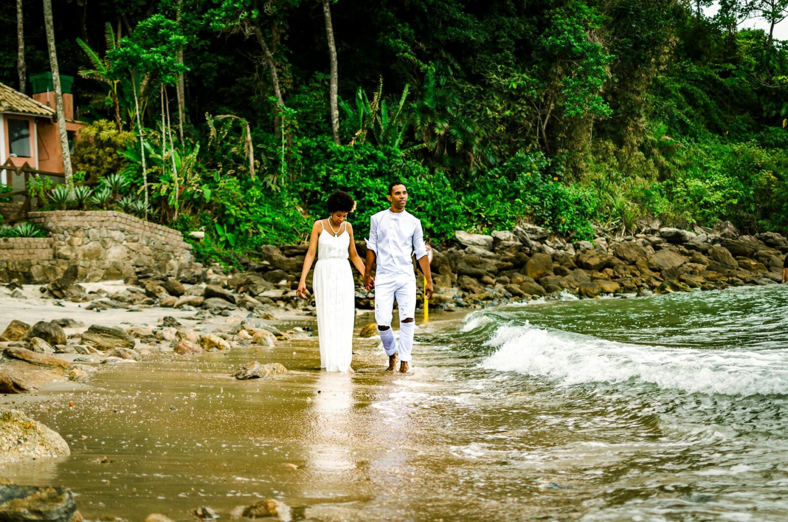 photo of couple walking on seashore