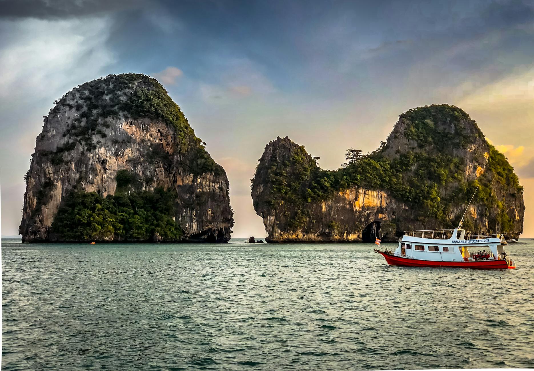 white boat sailing near islands during golden hour