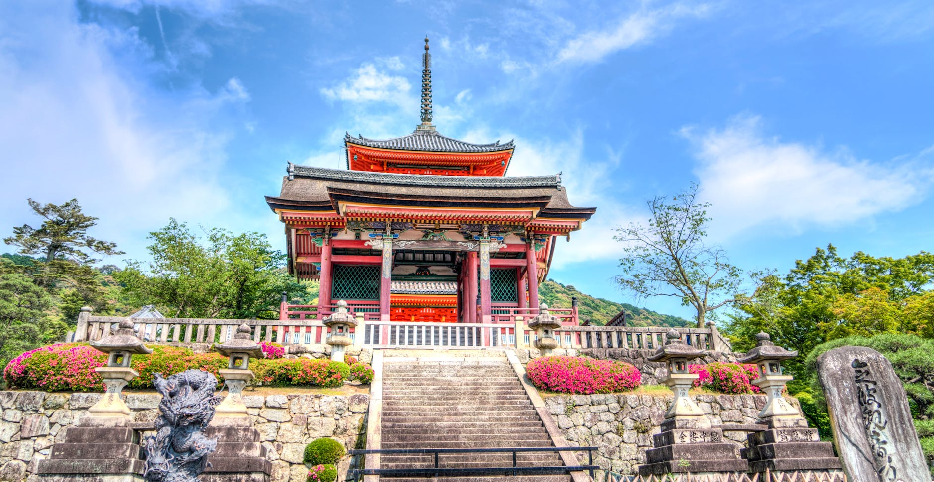 red black and white building structure surrounded by trees under white clouds during daytime